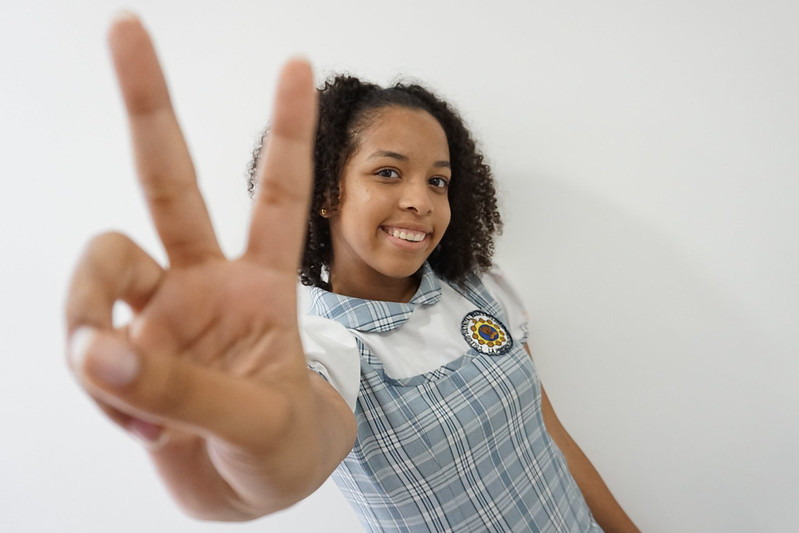 niña haciendo seña de V con la mano derecha